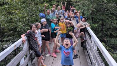 A group of children cheering on a wooden bridge