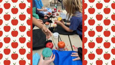 Elementary school students paint apples at a table.