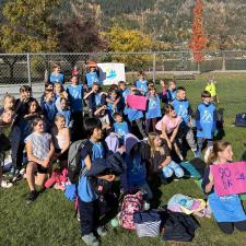 A group of elementary school students in a school field getting ready for a cross-country run on a sunny fall day